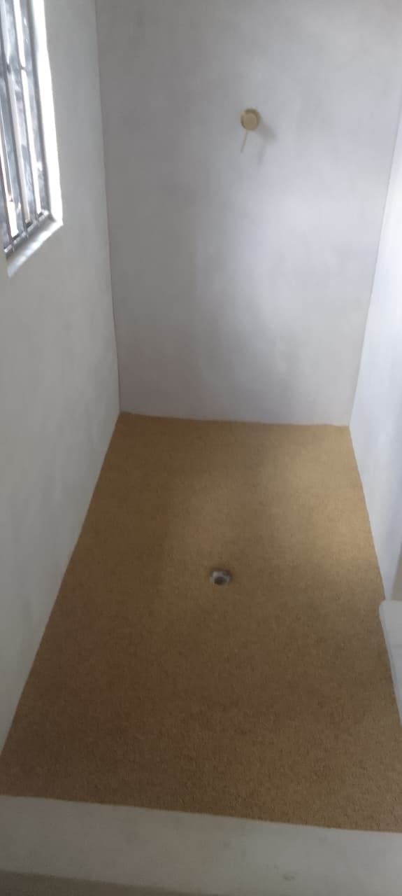 Site photo showing a shower floor laid with its drain in place, before the room is finished