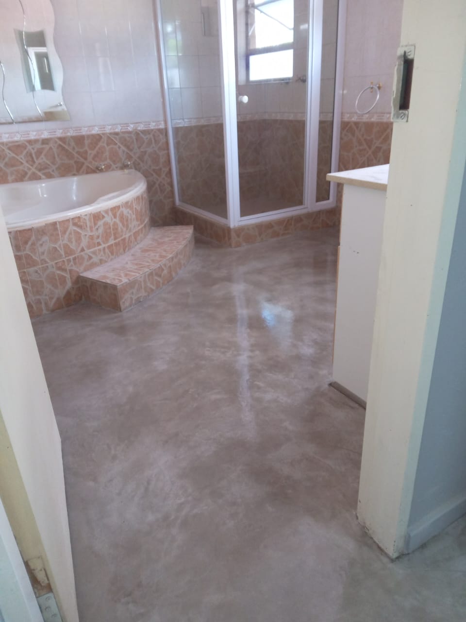 Project photo showing a finished floor in a bathroom with a built-in bathtub and shower enclosure