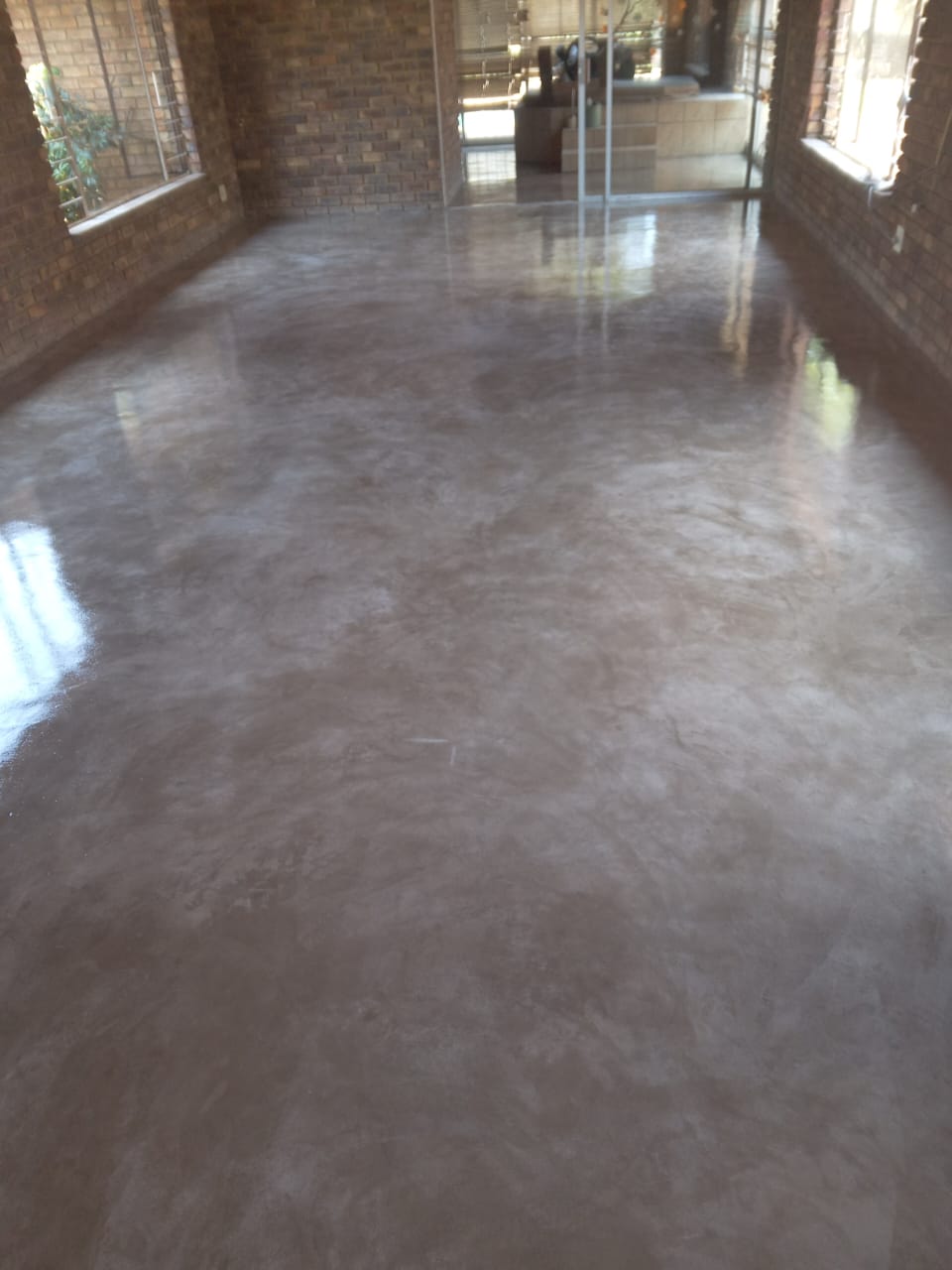 Project photo showing a polished floor finish in a sunlit room with face brick walls